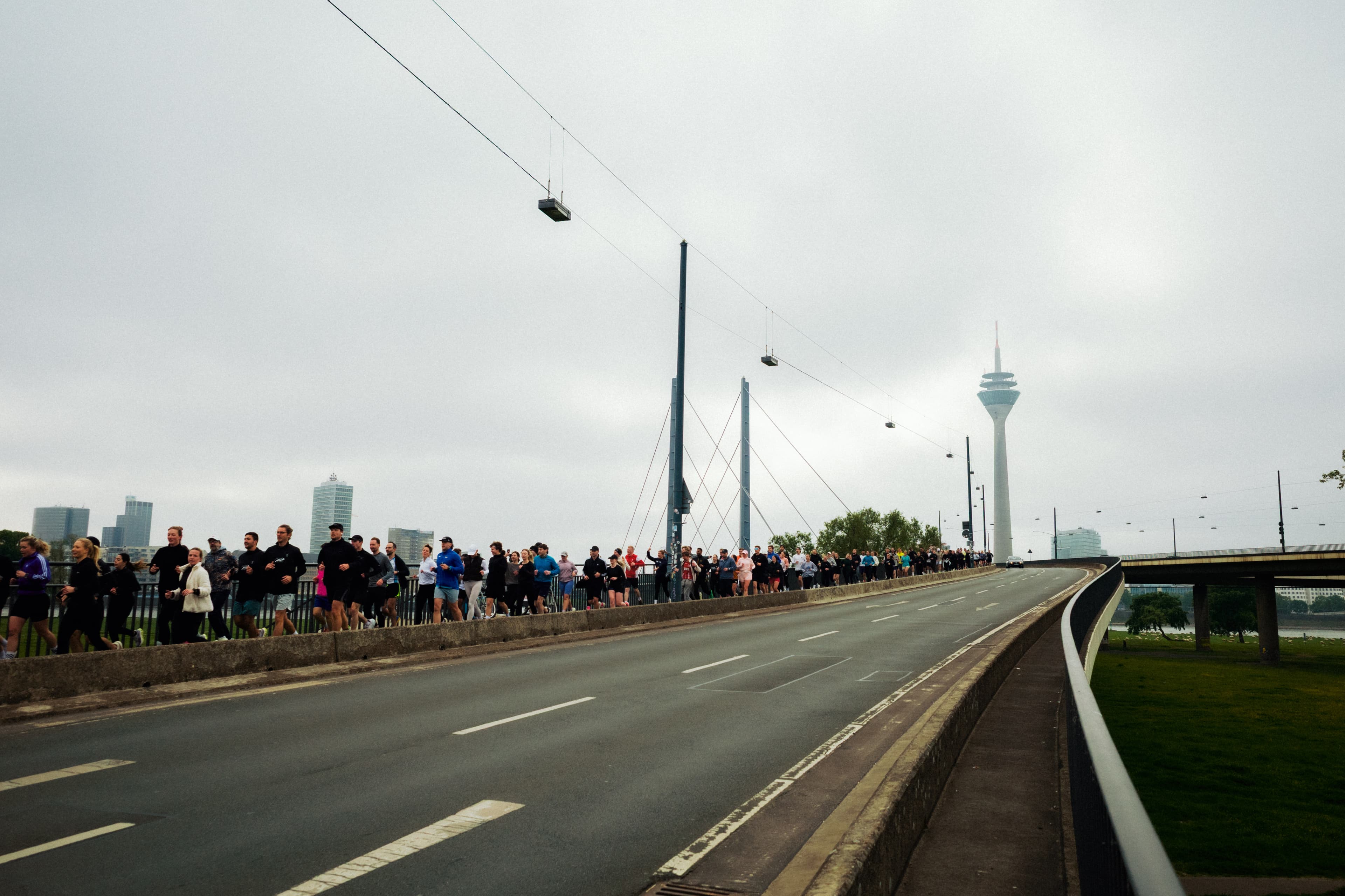 PAUS run-club crossing Rheinkniebrücke at sunrise, Düsseldorf